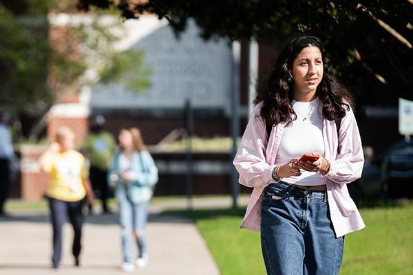 Student walking through campus with phone in hand