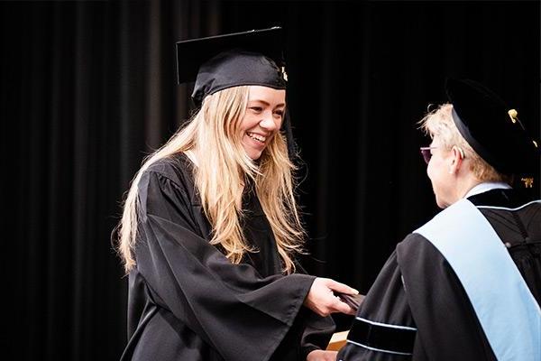 Student walking across stage accepting diploma 